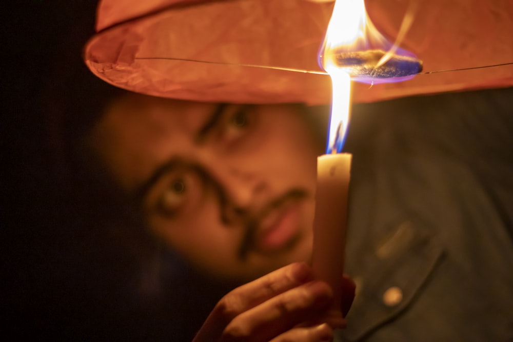 person holding lighted candle in front of man