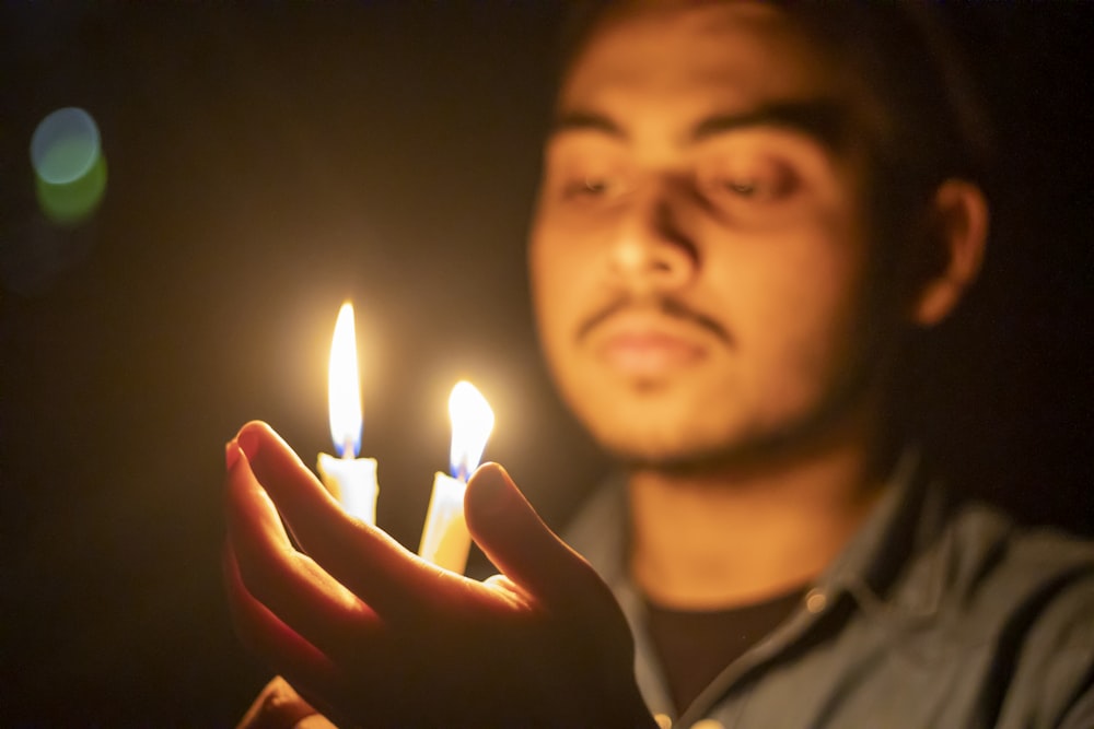 man in gray shirt holding lighted candle