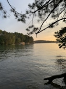 Sunset view over a serene lake with pine trees reflecting in the water.