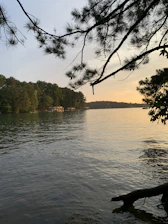 A serene lakeside view at sunset with soft sage green and warm beige tones.