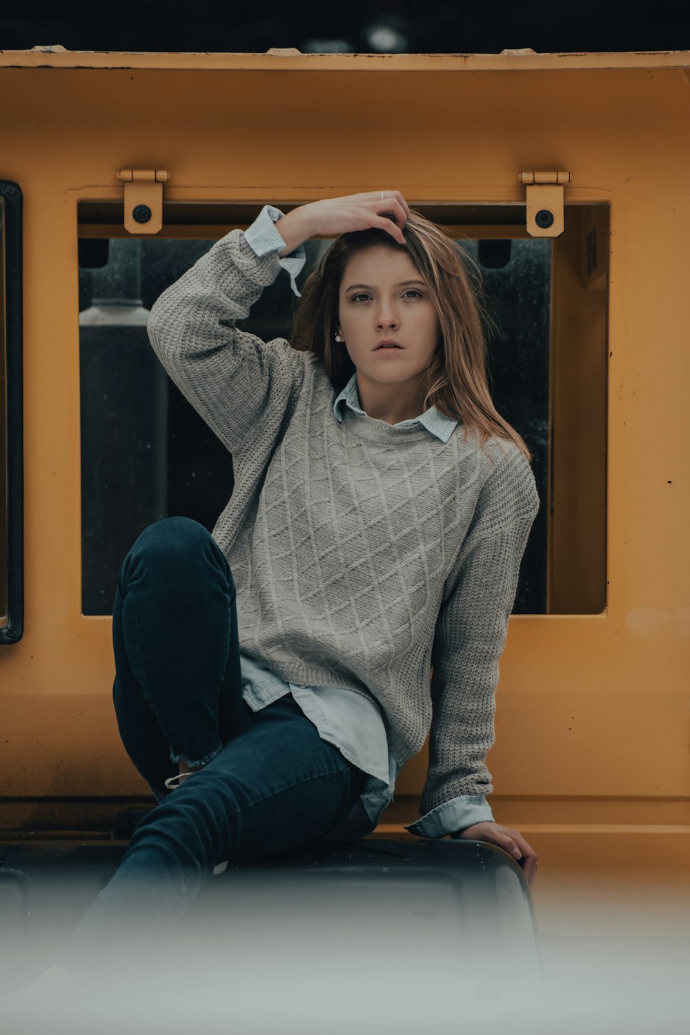 woman in white and black checkered dress shirt and blue denim jeans sitting on yellow wooden