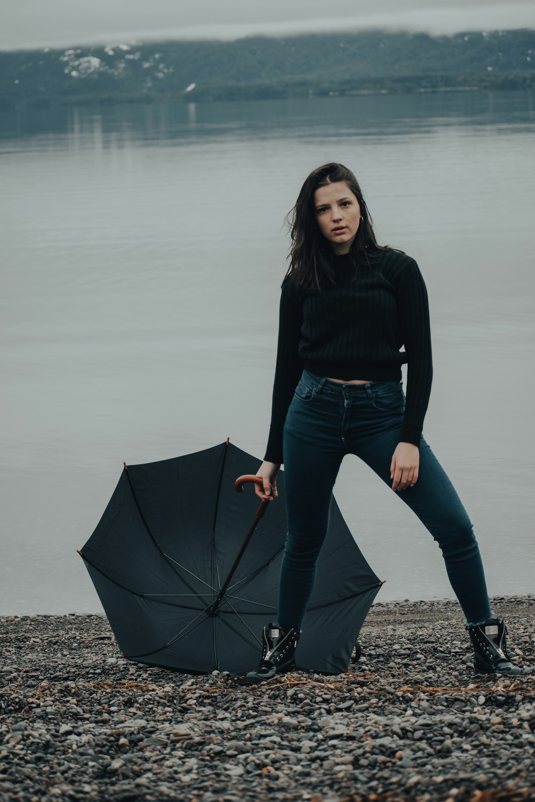 woman in black long sleeve shirt and blue denim jeans holding umbrella