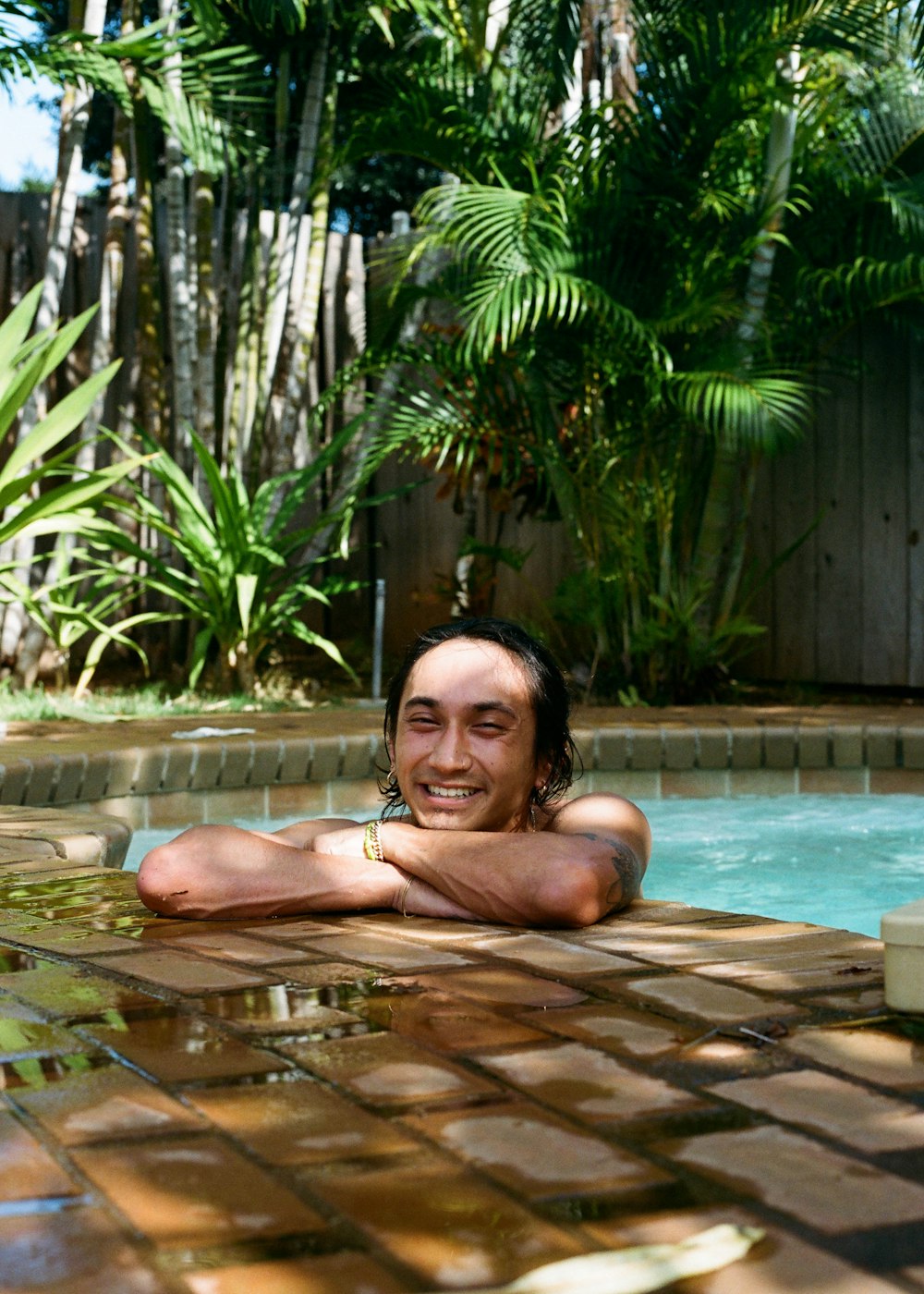 topless man lying on swimming pool during daytime