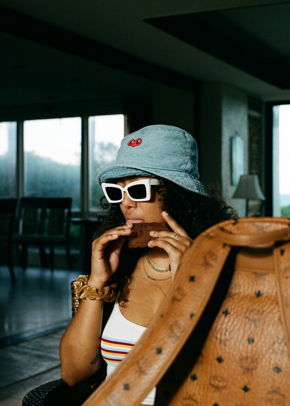 woman in gray cap and black sunglasses sitting on brown wooden chair