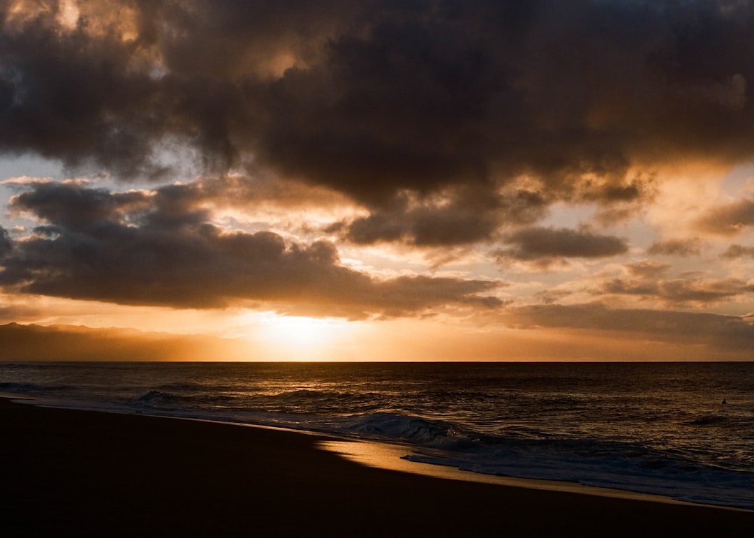 body of water under cloudy sky during sunset