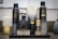 A neatly arranged set of Oribe hair care products sits on a granite countertop. The collection includes bottles and tubes of various sizes, predominantly black and gold in color. A large white candle and a decorative jar can be seen in the background, adding a touch of elegance to the setting.