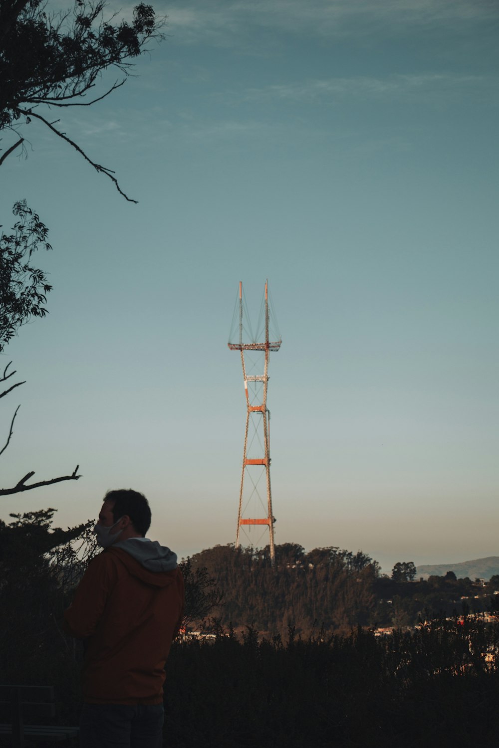 man in red hoodie standing near tower during daytime