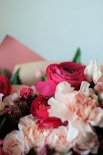 A close-up of a vibrant bouquet featuring roses, lilies, and wildflowers arranged with delicate greenery.