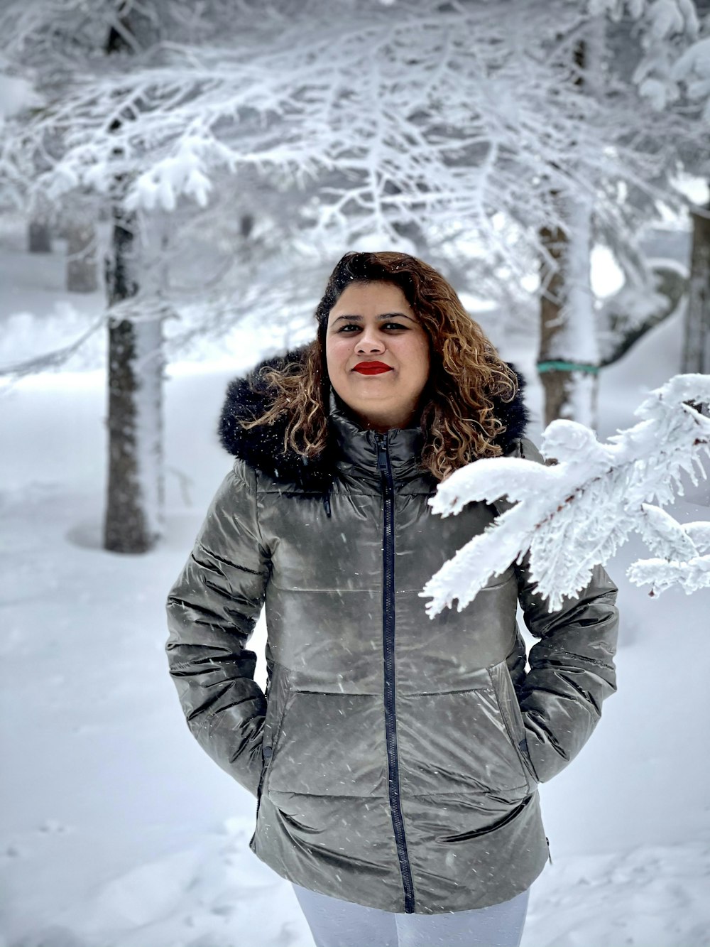 woman in gray winter coat standing on snow covered ground during daytime