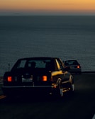 A convoy of cars driving along a coastal road in Senegal at sunset.