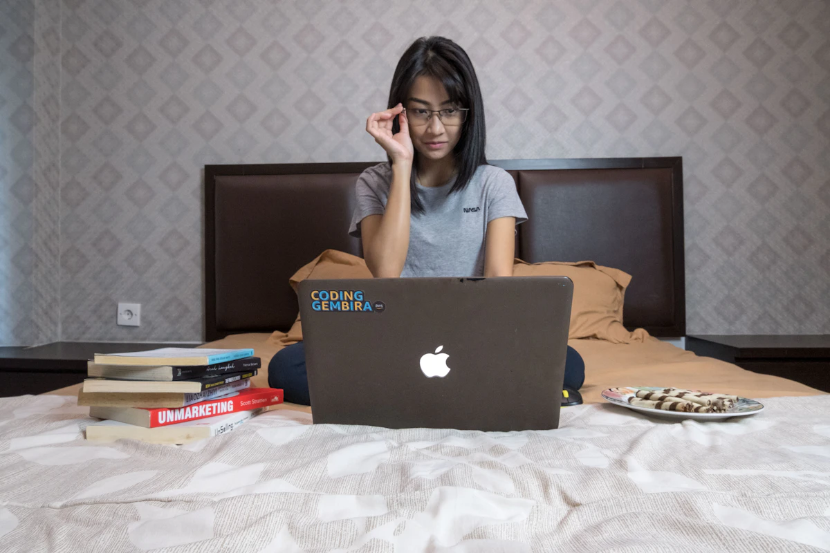 A young woman in a gray shirt working on a laptop from home