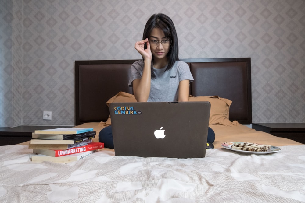 woman in gray shirt sitting in front of macbook