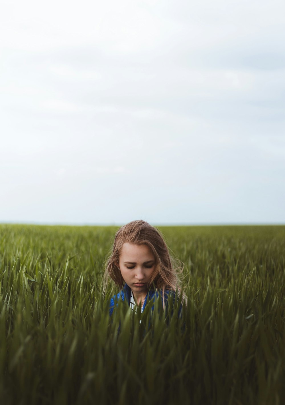 girl in blue and white shirt standing on green grass field during daytime