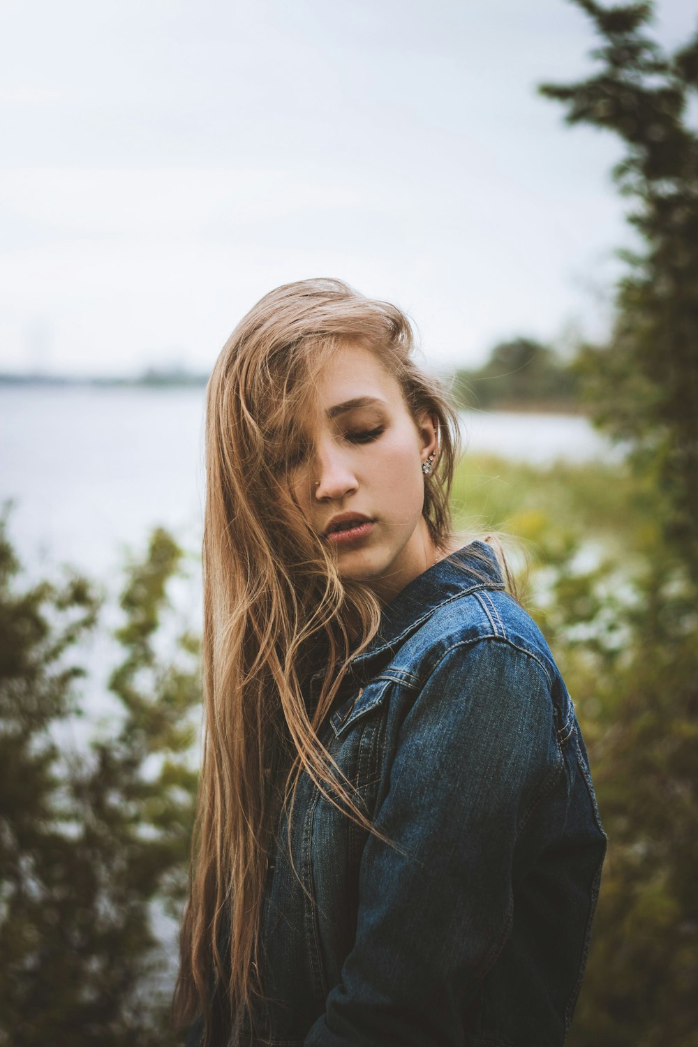 woman in blue denim jacket standing near body of water during daytime