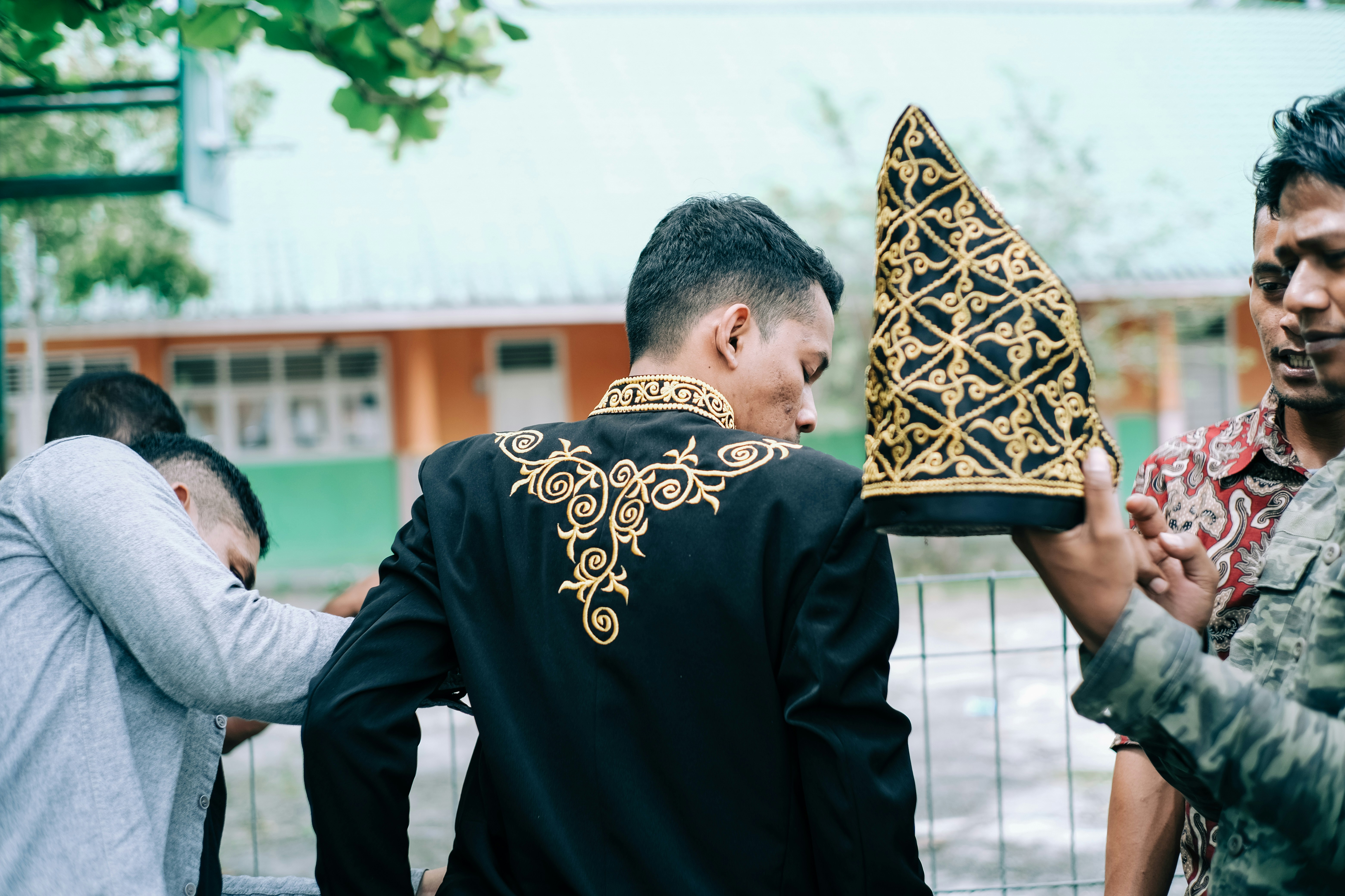 昼間、黒い金属製の柵のそばに立つ黒いセーターを着た男