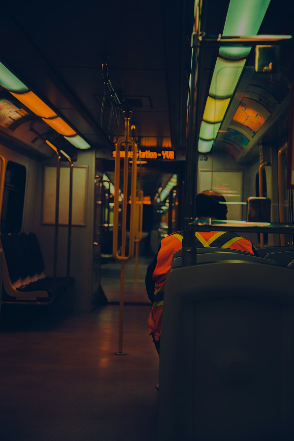 hombre en chaqueta naranja sentado en el asiento del tren