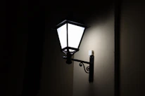 Elegant wall lantern casting a gentle light on a rustic porch during twilight.