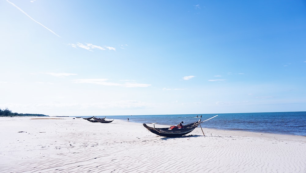 blue boat on white sand beach during daytime