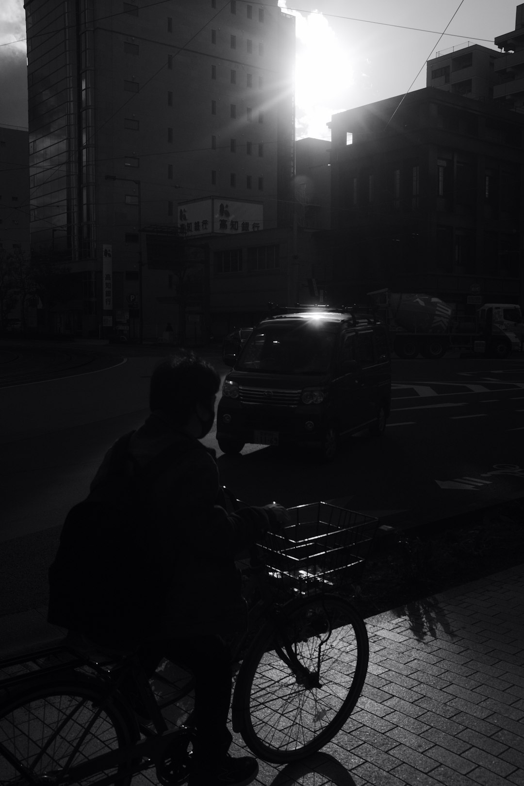 man in black jacket sitting on bench near car during night time