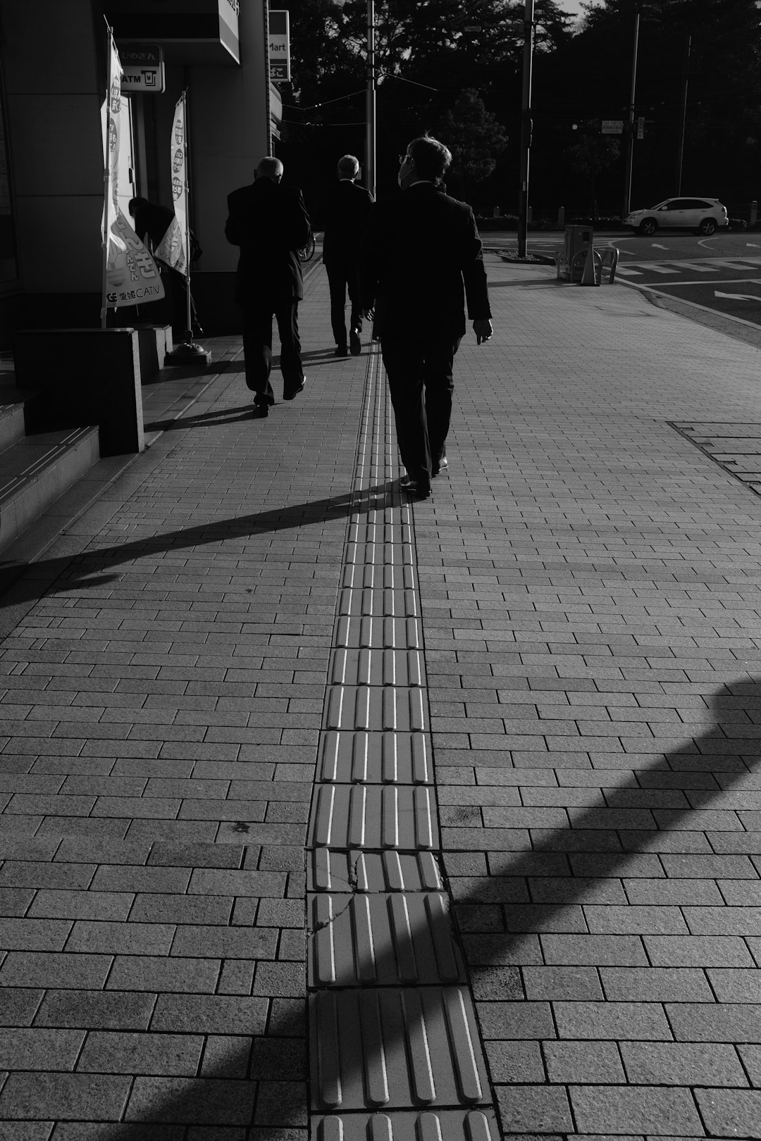 man in black jacket walking on sidewalk during daytime