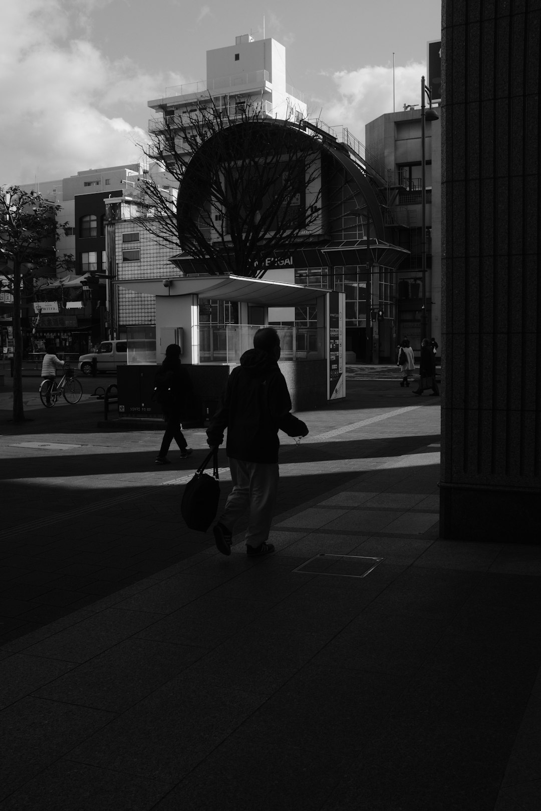 man in black jacket and pants walking on sidewalk during daytime