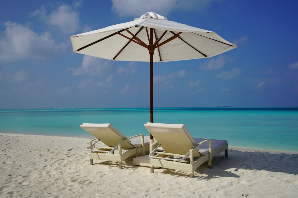 Parasol blanc et marron sur la plage de sable blanc pendant la journée