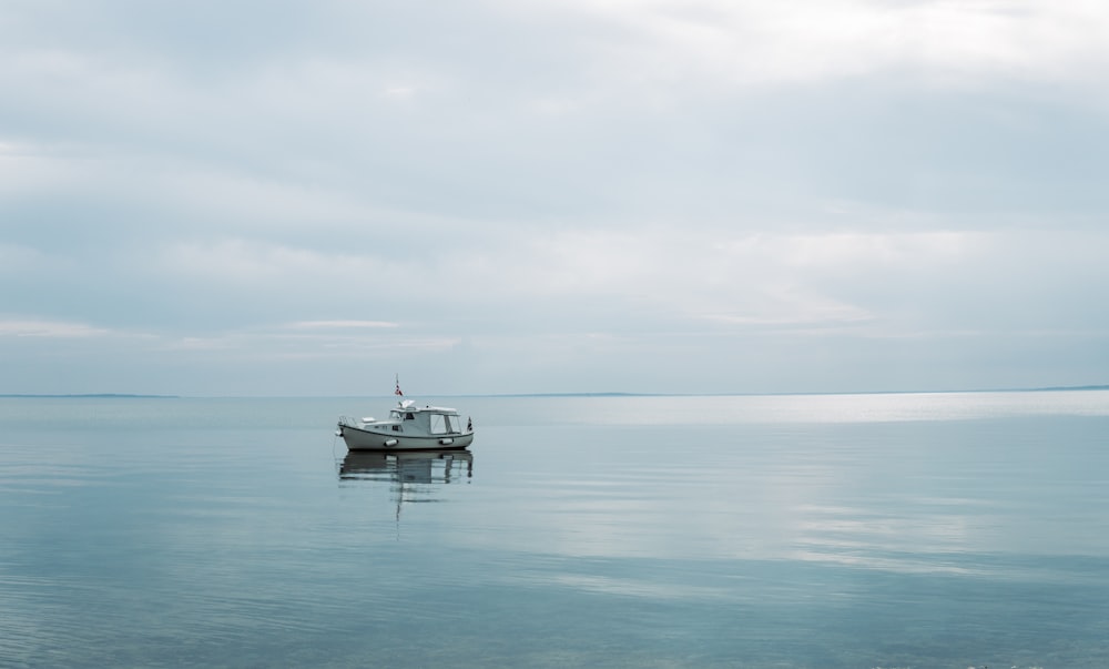 white boat on sea under white sky during daytime