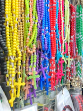 Display of elegant rosaries with gold accents against a cream background.
