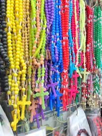 Colorful rosaries made with natural stones and delicate beads displayed on a wooden table.