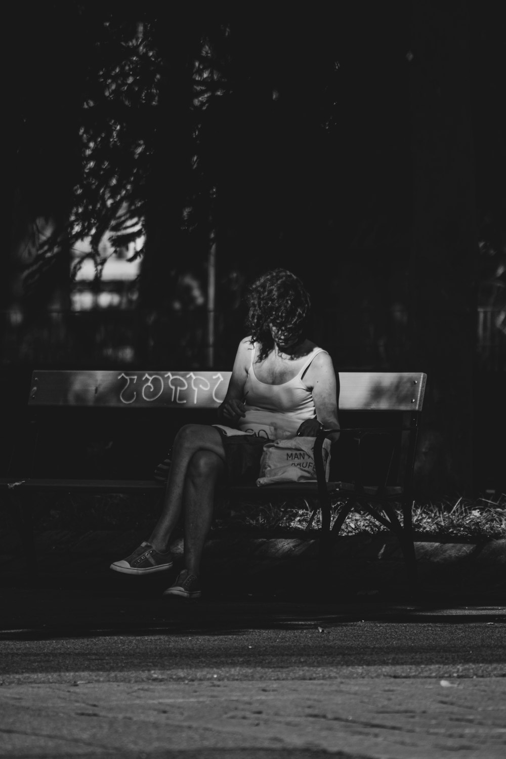 grayscale photo of woman sitting on bench