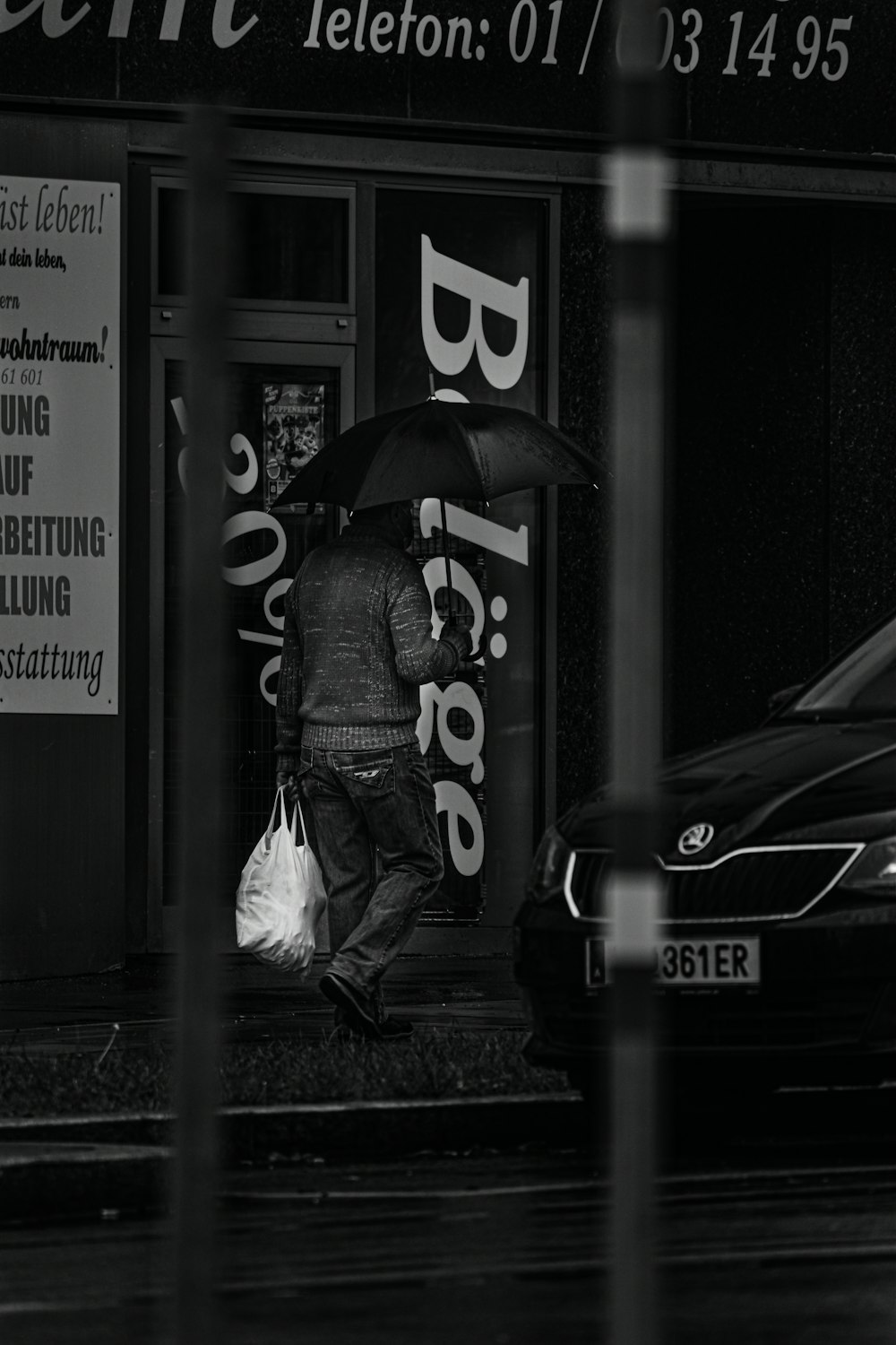 grayscale photo of woman in black jacket holding umbrella