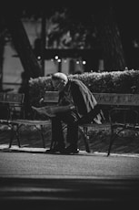 grayscale photo of man in jacket and pants standing near road