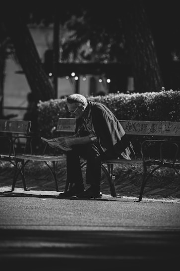 grayscale photo of man in jacket and pants standing near road