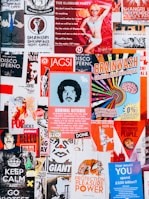A vibrant collage of posters with various colors and designs. The posters feature a mix of artistic illustrations, bold typography, and playful graphics. There are themes of independence, entertainment, and political statements with a retro vibe.