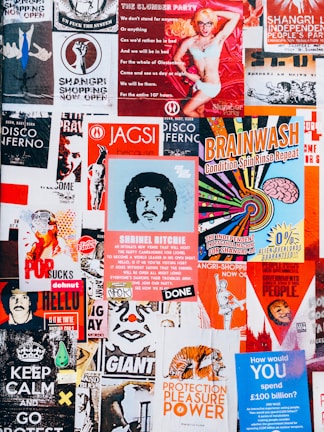 A vibrant collage of posters with various colors and designs. The posters feature a mix of artistic illustrations, bold typography, and playful graphics. There are themes of independence, entertainment, and political statements with a retro vibe.