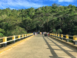 A vibrant gravel event with riders crossing a wooden bridge.