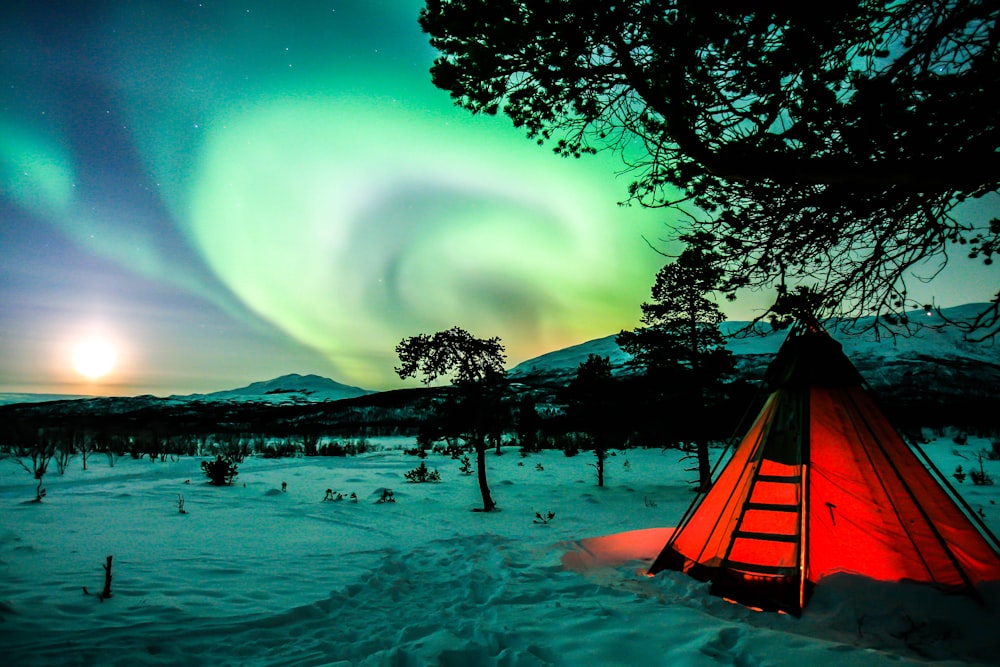 tenda arancione su terreno innevato durante la notte