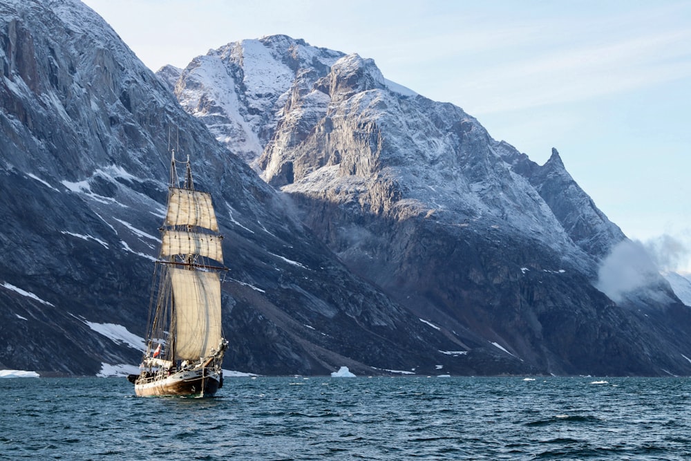 brown and white boat on sea near mountain during daytime