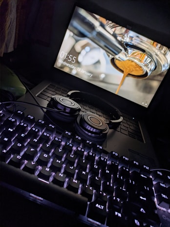 black computer keyboard beside black and silver headphones
