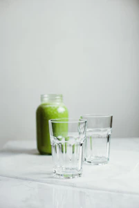 A bright, airy kitchen scene with fresh greens, supplements, and a person preparing a healthy smoothie.