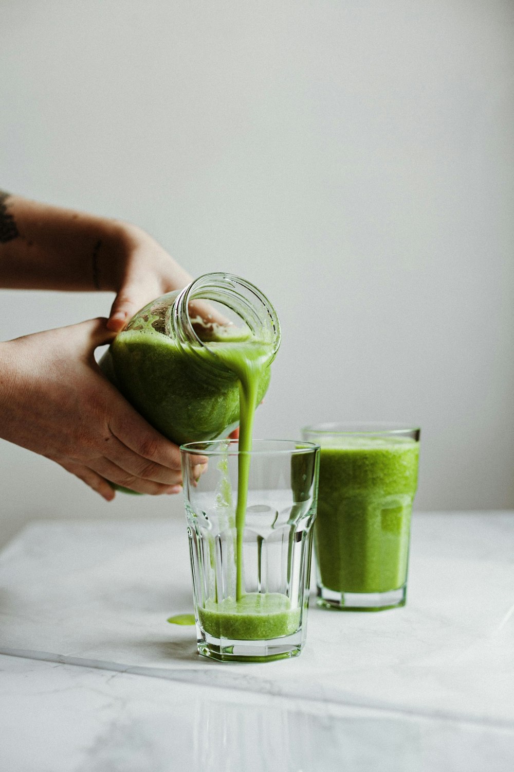 Persona che tiene un bicchiere trasparente con liquido verde