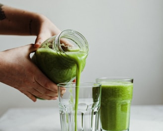 person holding clear drinking glass with green liquid