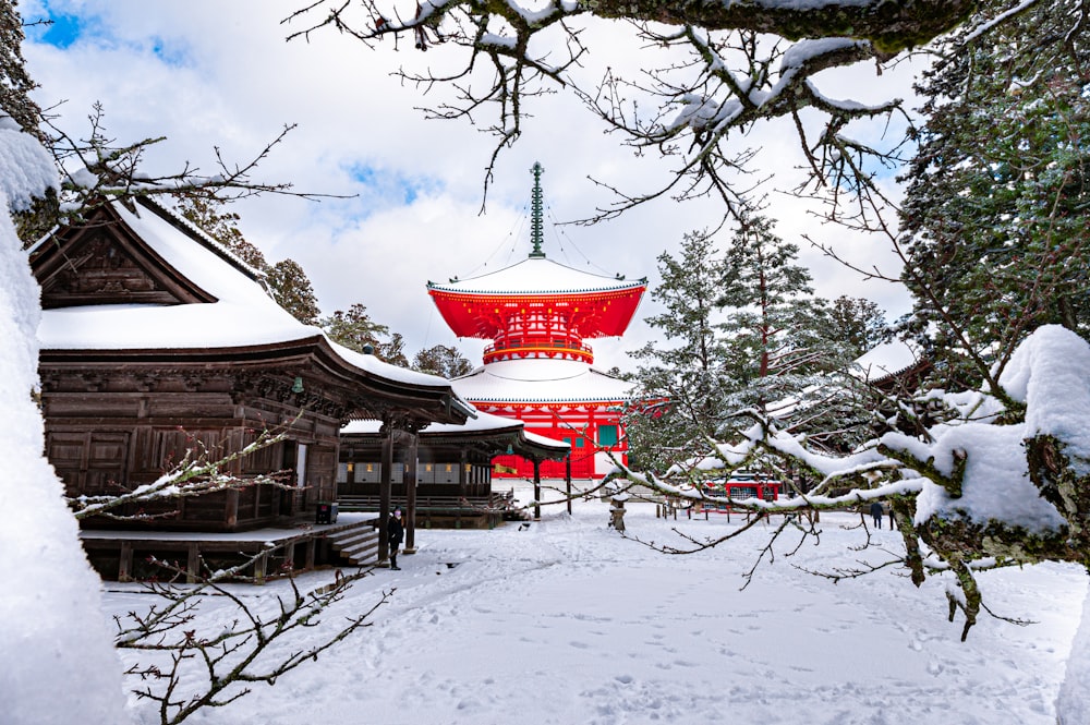 red and white temple surrounded by trees covered with snow