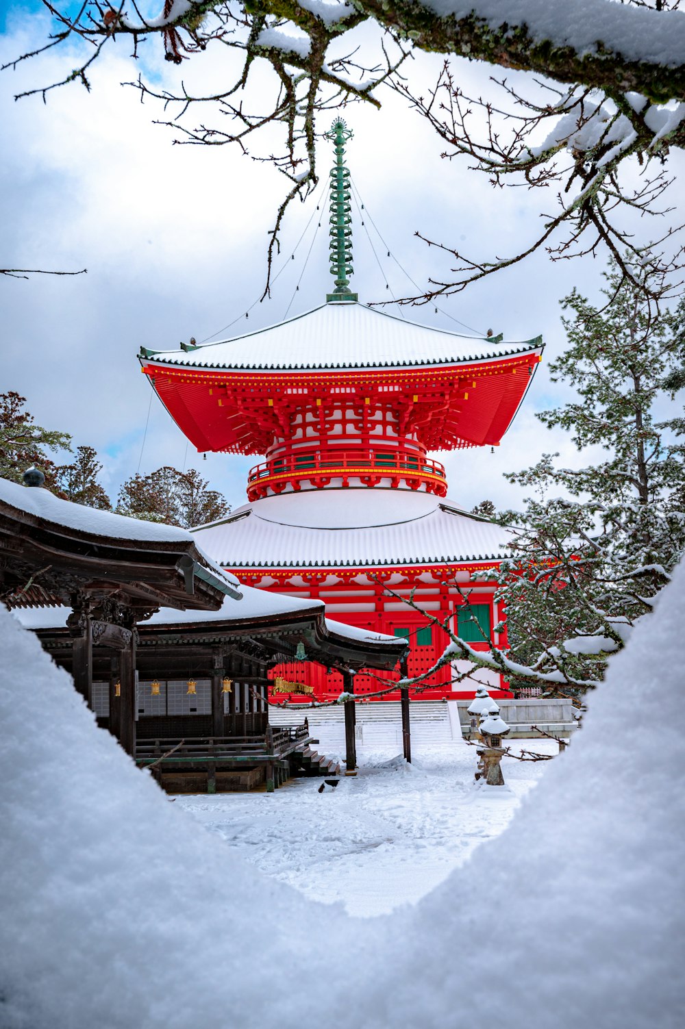 red and white temple surrounded by trees covered with snow