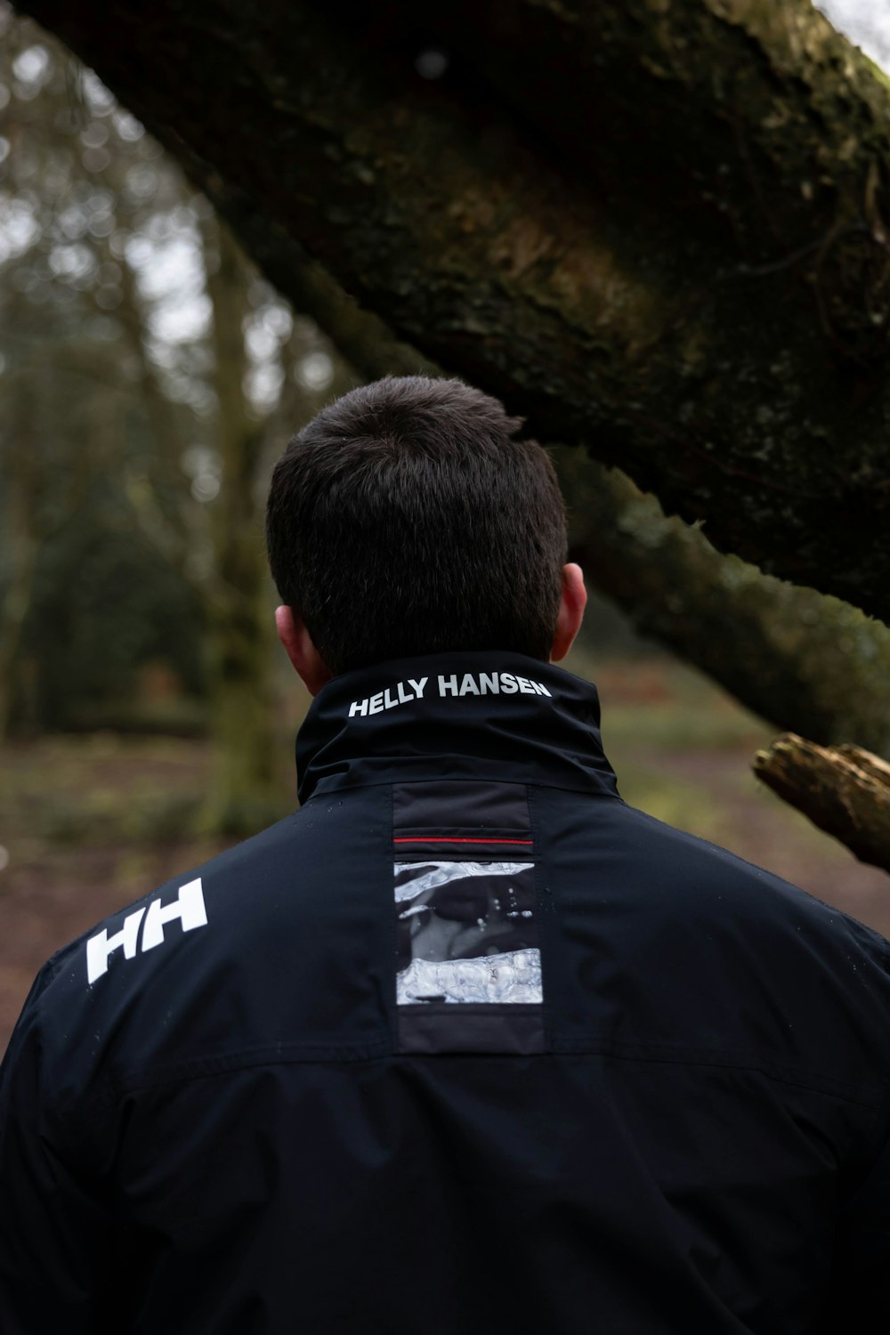 man in black jacket standing beside brown tree during daytime