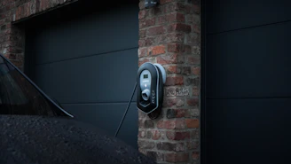A skilled electrician installing a modern EV charger in a residential driveway.