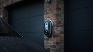 A professional technician installing an electric vehicle charger in a modern São Paulo home garage.