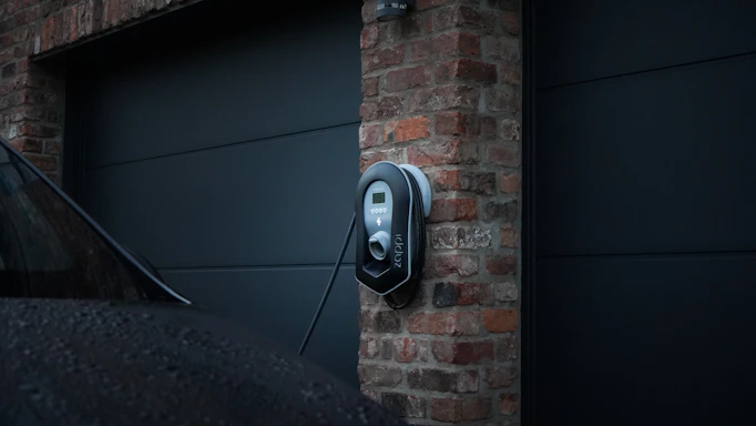 A professional technician installing an electric vehicle charger in a modern São Paulo home garage.