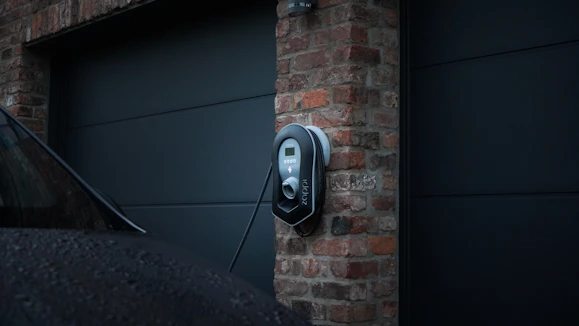 A skilled electrician installing a modern EV charger in a residential driveway.