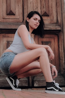 woman in gray tank top and blue denim shorts sitting on brown wooden bench
